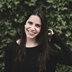 Photo by Sayo Garcia a smiling woman in a black top stands in front of a bush